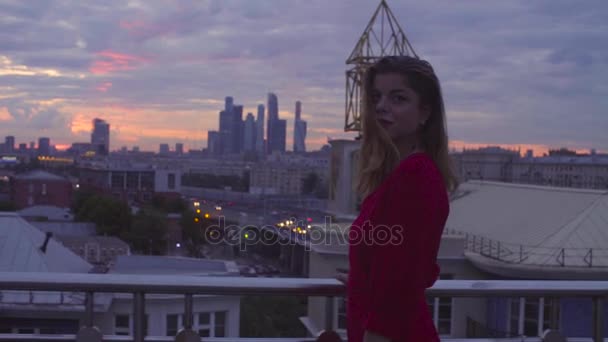 Piros ruhás fiatal nő áll, parapet közelében — Stock videók