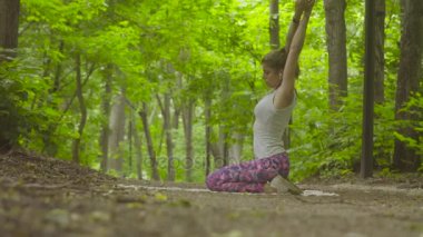 Parkta yoga egzersizi yapan genç bir kadın.