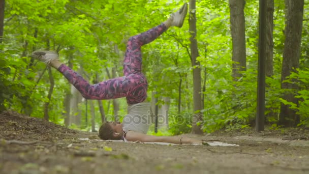 Jonge vrouw doet yoga oefeningen in het park — Stockvideo