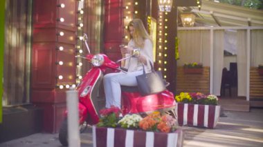 Scooter üzerinde oturan genç kadın portresi