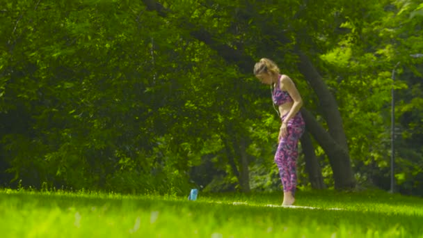 Mujer joven haciendo ejercicios de yoga en el parque — Vídeo de stock