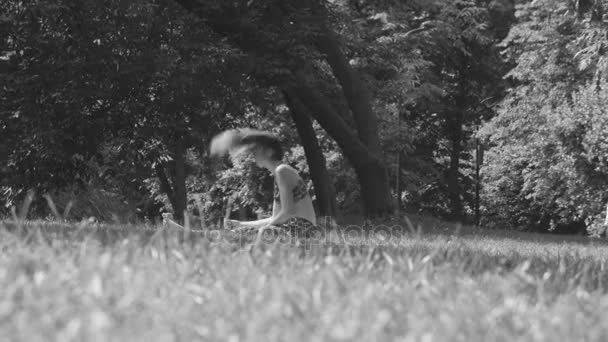 Young woman sitting on the grass in the park — Stock Video