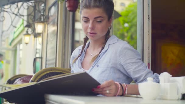 Портрет молодой женщины, читающей меню в кафе — стоковое видео