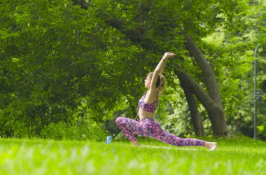 Parkta yoga egzersizi yapan genç bir kadın.