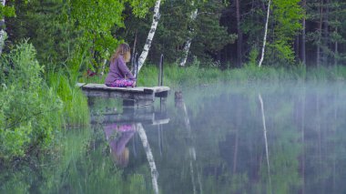 genç kadın bir göl kıyısında meditasyon