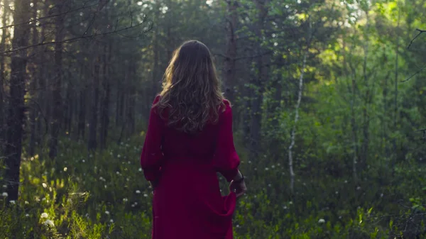 Fiatal nő piros ruhában séta az erdőben — Stock Fotó