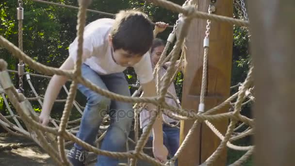 Een jongen en de moeder klimmen op een speeltoestellen — Stockvideo