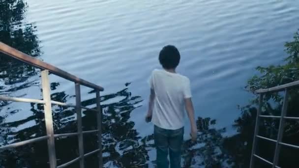 Хлопчик кидає камінці у воду — стокове відео