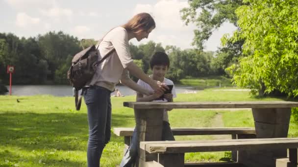 Menino jogando um tablet em um parque . — Vídeo de Stock