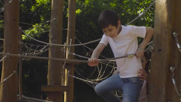 Un garçon grimpant sur un équipement de terrain de jeu — Video