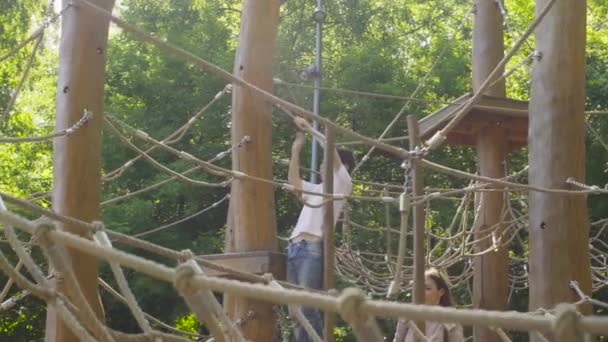 Un niño trepando en un parque infantil — Vídeo de stock