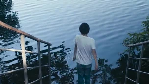 Der Junge wirft Kieselsteine ins Wasser — Stockvideo