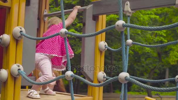 Pequena menina caminhando em um playground corda — Vídeo de Stock