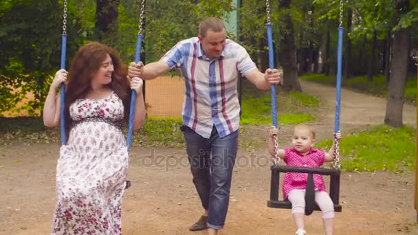 Hombre balanceando a su hija y su esposa en un columpio — Vídeos de Stock