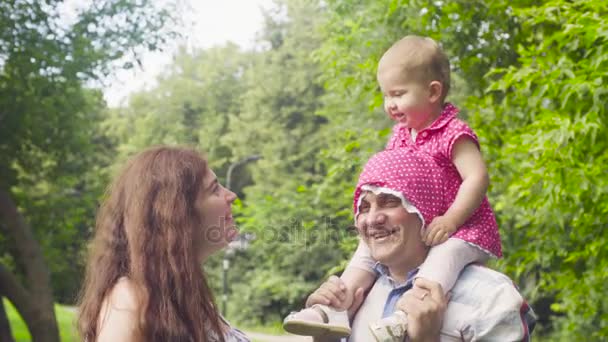 Een baby die zittend op de schouders van een vaders — Stockvideo