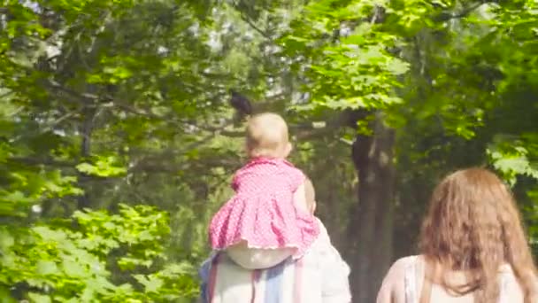 Счастливые родители с маленькой девочкой гуляют в парке — стоковое видео