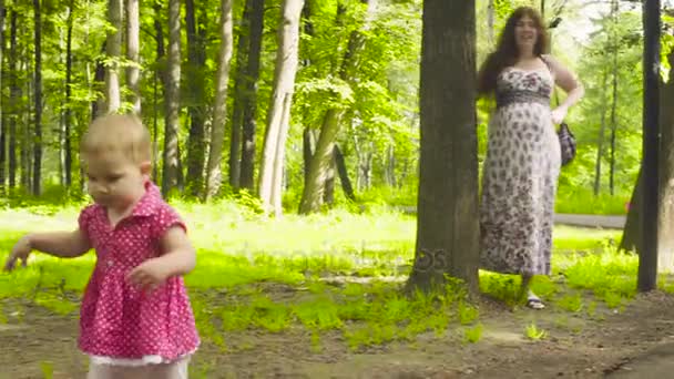 Lyckliga föräldrar med baby flicka promenera i en park — Stockvideo