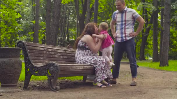 W ciąży mama i dziecko dziewczyna siedzi na ławce — Wideo stockowe