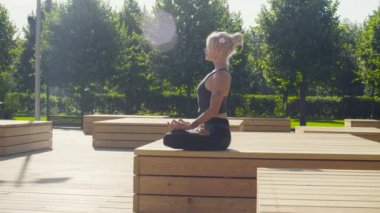 Genç bir kadın parkta meditasyon yapıyor.