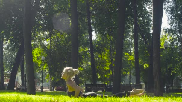 Ung kvinna som tränar yoga i parken — Stockvideo