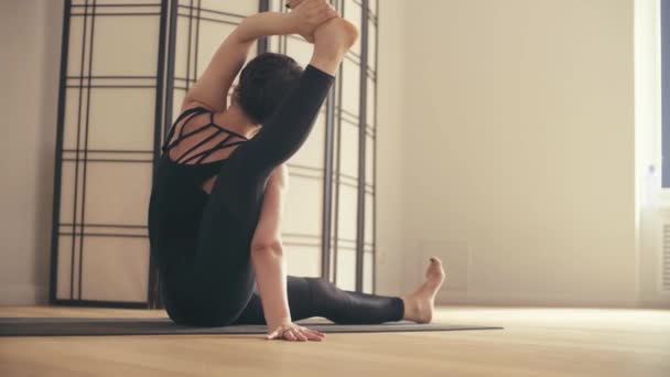 Een jonge vrouw uitvoeren van yoga-asana's in de zaal. — Stockvideo
