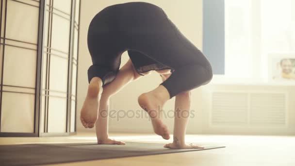 En ung kvinna som utför yoga-asanas i hallen. — Stockvideo