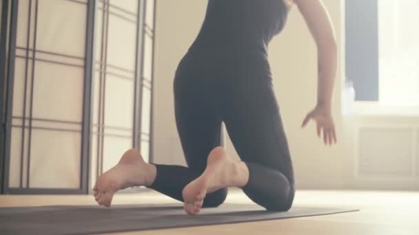 eine junge Frau führt Yoga-Asanas in der Halle vor.