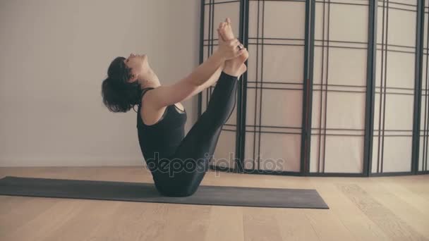 Eine junge Frau führt Yoga-Asanas in der Halle vor. — Stockvideo