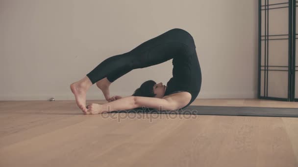 En ung kvinna som utför yoga-asanas i hallen. — Stockvideo