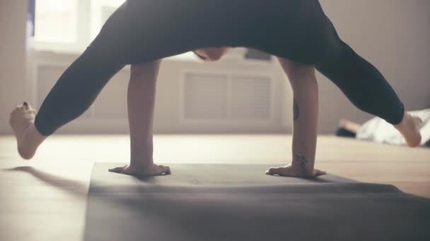 Eine junge Frau führt Yoga-Asanas in der Halle vor. — Stockvideo