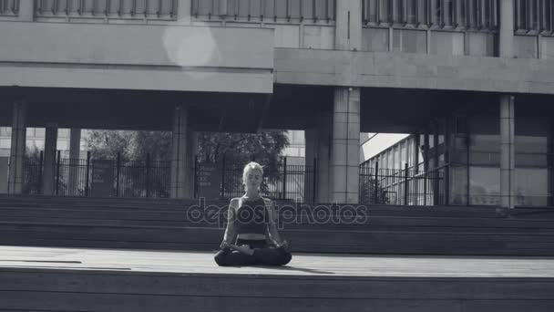 Jovem mulher meditando contra o edifício moderno — Vídeo de Stock