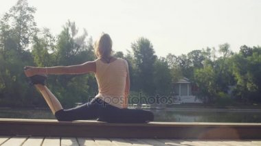 Parkta yoga egzersizi yapan genç bir kadın.