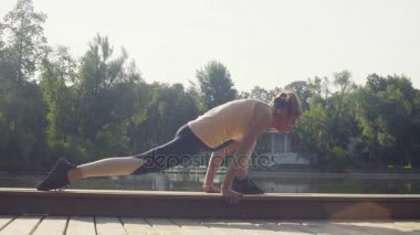 Parkta yoga egzersizi yapan genç bir kadın.