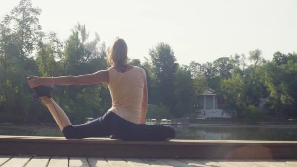 Ung kvinna som tränar yoga i parken — Stockvideo