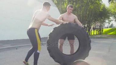 İki genç adam bir tekerlek crossfit egzersiz yapmak için haddeleme