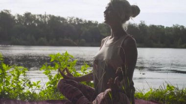 Nehir kıyısında üzerinde yoga egzersizleri yapıyor kadın