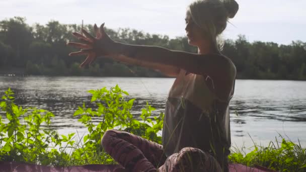 Жінка займається вправами йоги на березі річки — стокове відео