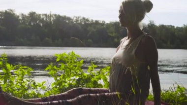 Nehir kıyısında üzerinde yoga egzersizleri yapıyor kadın