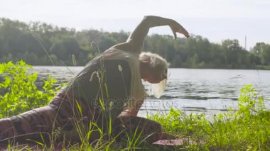 Nehir kıyısında üzerinde yoga egzersizleri yapıyor kadın
