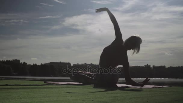 Mladá žena, která dělá cvičení jógy na břehu řeky — Stock video