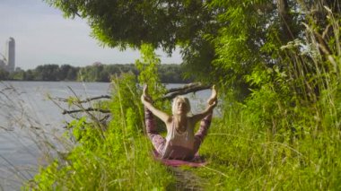 Nehir kıyısında üzerinde yoga egzersizleri yapıyor kadın