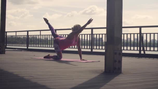 Приваблива жінка займається вправами йоги на відкритому повітрі — стокове відео