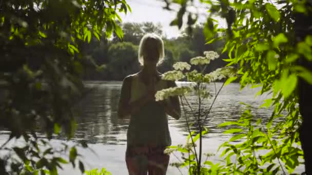 Woman doing yoga exercises on the river bank — Stock Video