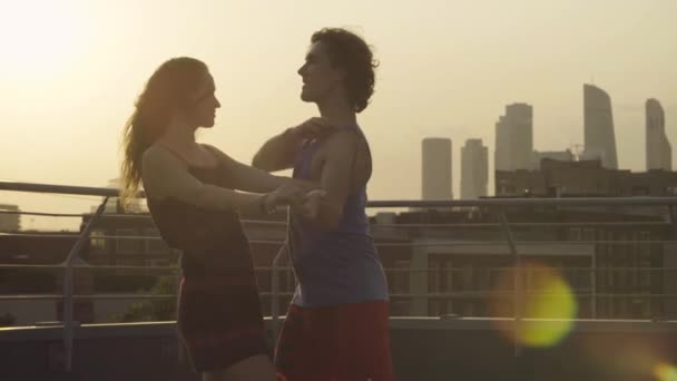Силуети молодої пари танцюють на заході сонця — стокове відео