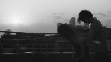 Genç çiftin günbatımı üzerinde dans siluetleri