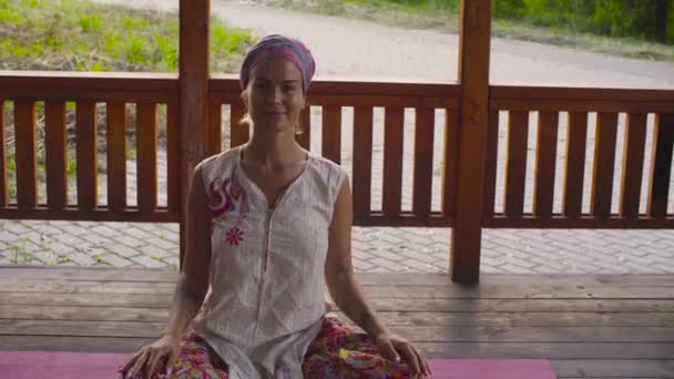 Приваблива жінка сидить на веранді в padmasana — стокове відео