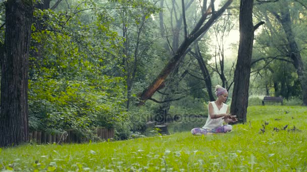 Žena sedí poblíž řeky s zpívající mísy — Stock video