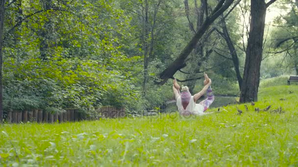 Kvinnan gör yogaövningar nära floden — Stockvideo