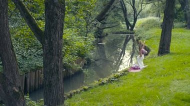 Kadının Nehri yakınında yoga egzersizleri yapması