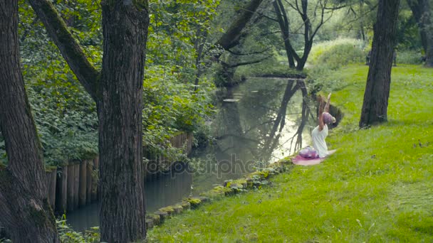 Vrouw doen yoga oefeningen in de buurt van de rivier — Stockvideo